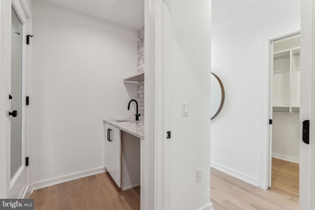 laundry area featuring sink and light hardwood / wood-style flooring