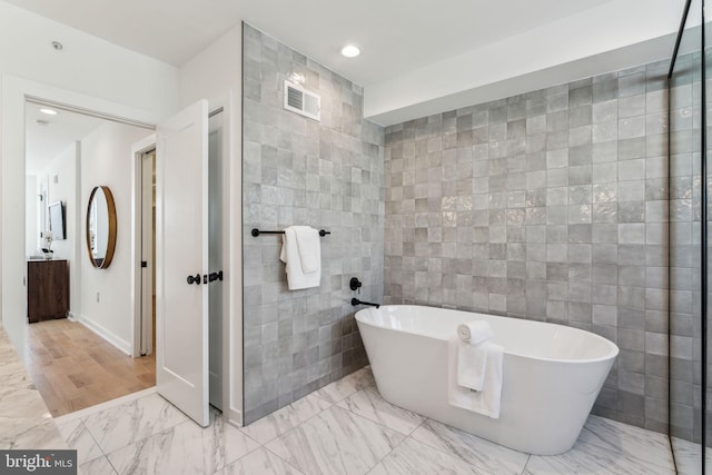 bathroom featuring tile walls and a bathtub