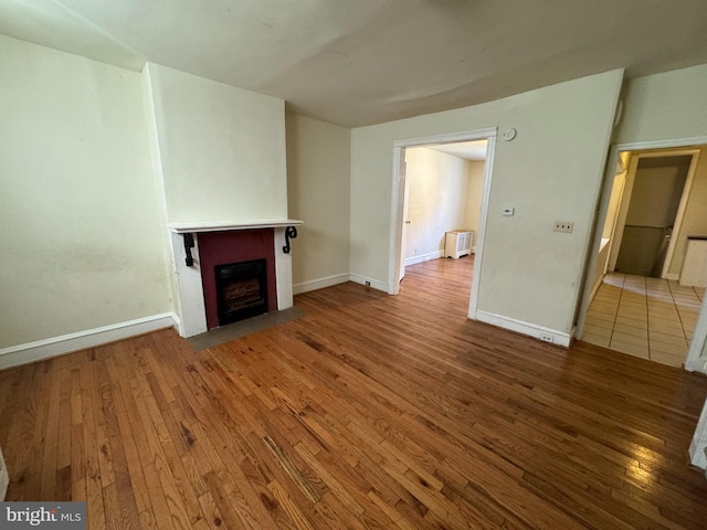 unfurnished living room featuring radiator heating unit and hardwood / wood-style floors