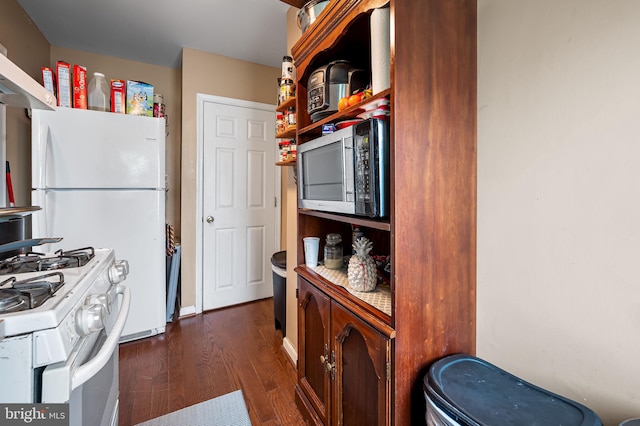 kitchen with dark wood-type flooring, white appliances, and wall chimney range hood