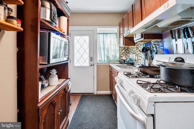 kitchen featuring sink, backsplash, and white gas range oven