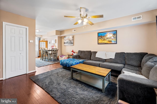 living room featuring dark wood-type flooring and ceiling fan