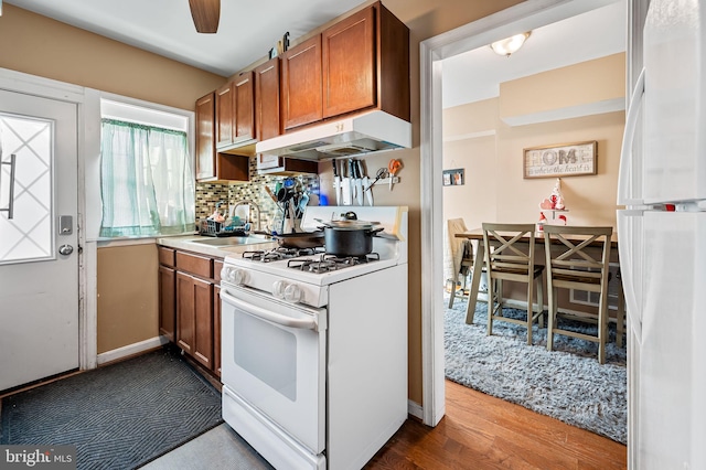 kitchen featuring sink, tasteful backsplash, light hardwood / wood-style flooring, ceiling fan, and white appliances