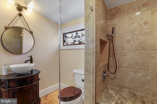 full bath with baseboards, toilet, vanity, and a tile shower