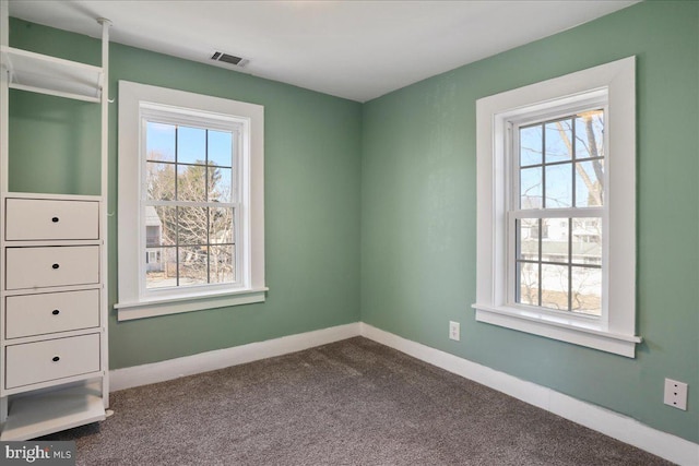 interior space featuring visible vents, dark carpet, and multiple windows