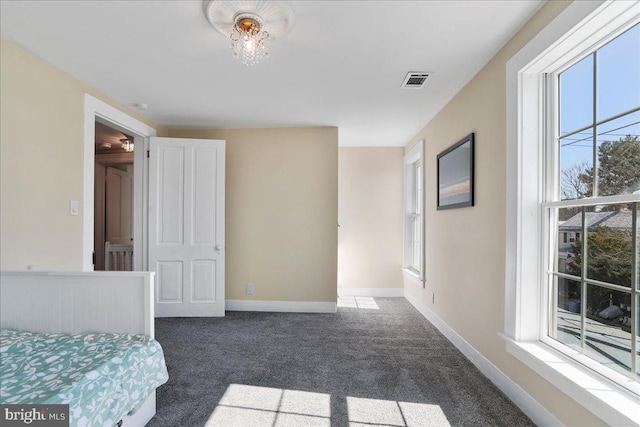 bedroom with dark colored carpet, visible vents, and baseboards