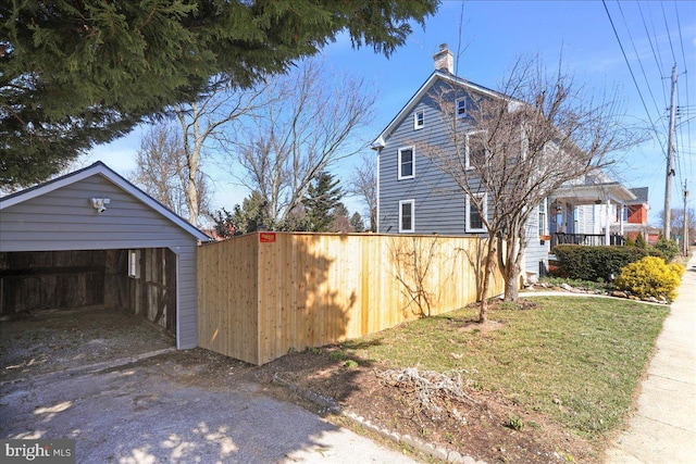 view of home's exterior featuring a chimney, a detached garage, and a yard