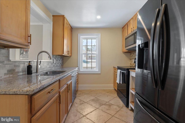 kitchen featuring light stone counters, baseboards, a sink, black appliances, and tasteful backsplash