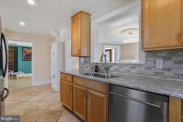 kitchen featuring backsplash, baseboards, light stone countertops, appliances with stainless steel finishes, and a sink