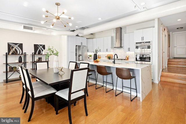 dining space featuring sink, a chandelier, and light hardwood / wood-style flooring