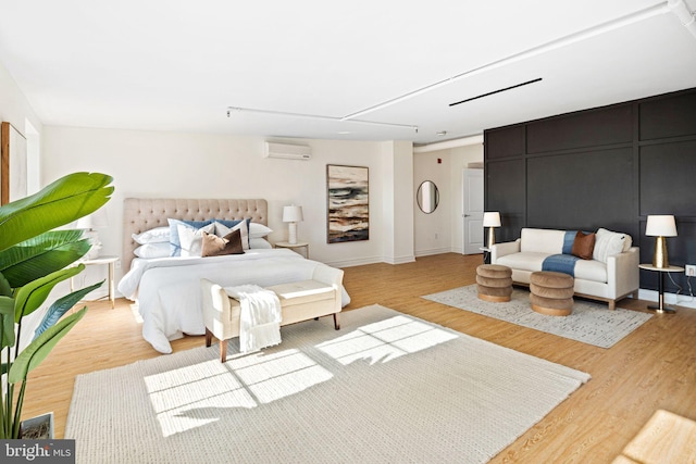 bedroom with a wall unit AC and light wood-type flooring