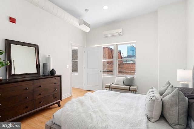 bedroom featuring light hardwood / wood-style flooring and a wall unit AC