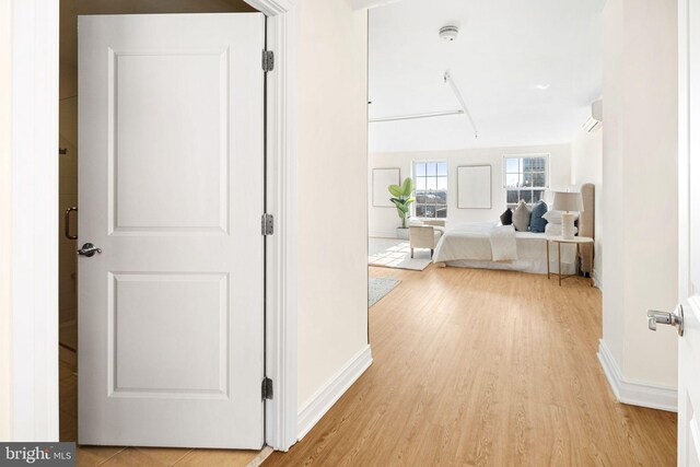 hallway featuring light wood-type flooring and a wall unit AC