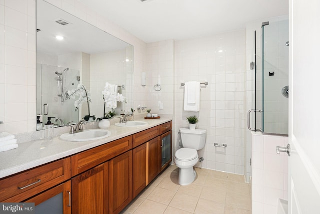 bathroom featuring tile walls, a shower with door, vanity, and tile patterned flooring