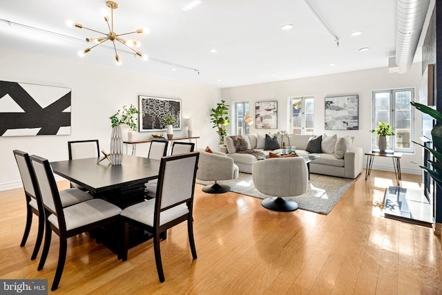 dining area with light hardwood / wood-style flooring, track lighting, and a chandelier