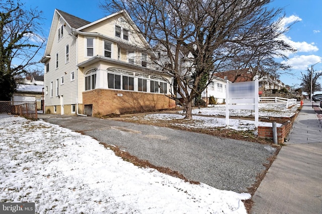 view of snowy exterior with a sunroom