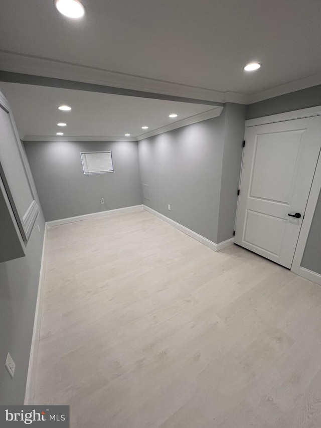 basement with ornamental molding and light hardwood / wood-style flooring