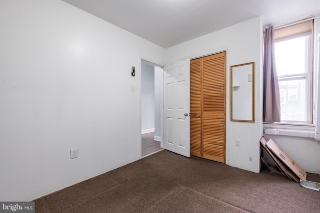 unfurnished bedroom featuring a closet and dark colored carpet