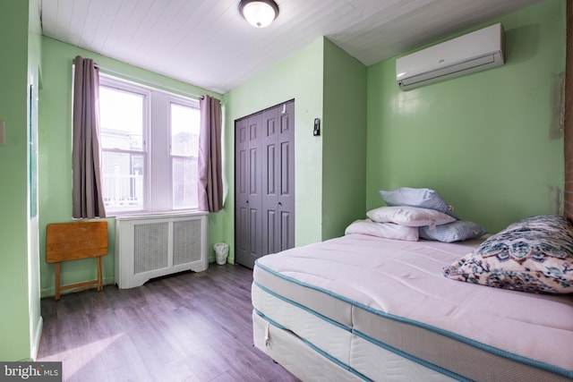 bedroom with light hardwood / wood-style flooring, radiator, a closet, and a wall mounted air conditioner