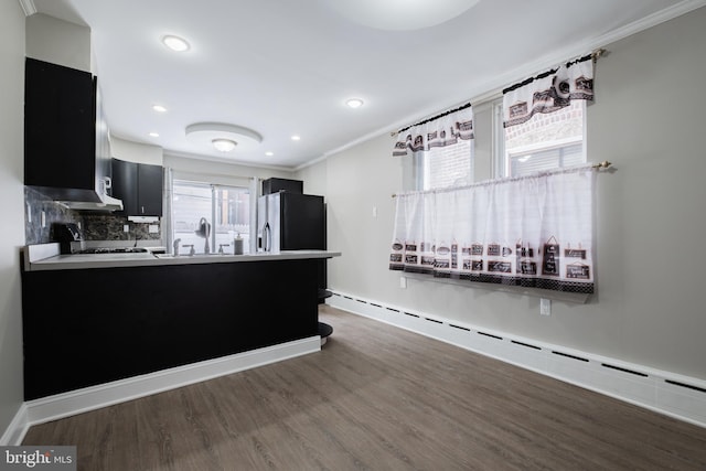 kitchen with dark hardwood / wood-style floors, kitchen peninsula, baseboard heating, and tasteful backsplash