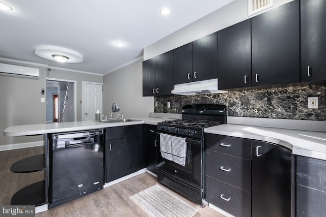 kitchen with an AC wall unit, black appliances, tasteful backsplash, kitchen peninsula, and light hardwood / wood-style flooring