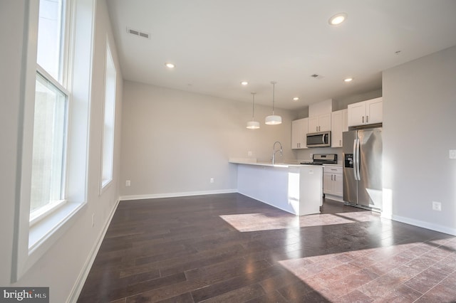 kitchen with white cabinetry, kitchen peninsula, stainless steel appliances, dark wood-type flooring, and hanging light fixtures