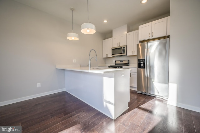 kitchen featuring decorative light fixtures, kitchen peninsula, appliances with stainless steel finishes, and white cabinetry