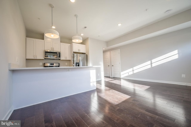 kitchen with dark hardwood / wood-style floors, appliances with stainless steel finishes, pendant lighting, and white cabinets