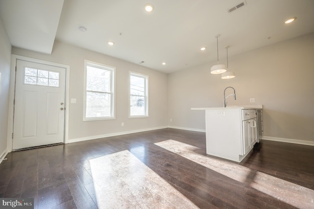 kitchen with dark hardwood / wood-style flooring, sink, white cabinets, and decorative light fixtures