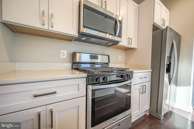 kitchen with white cabinets, light stone countertops, stainless steel appliances, and dark hardwood / wood-style floors