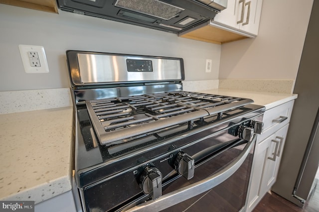 room details with white cabinets and black gas range