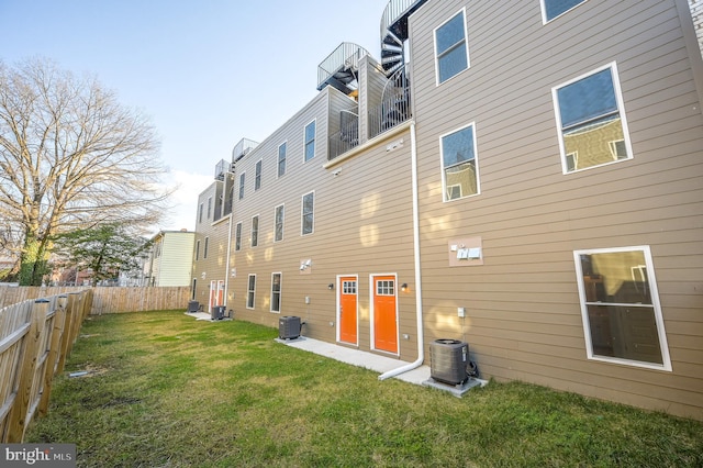 rear view of property featuring a yard and central air condition unit