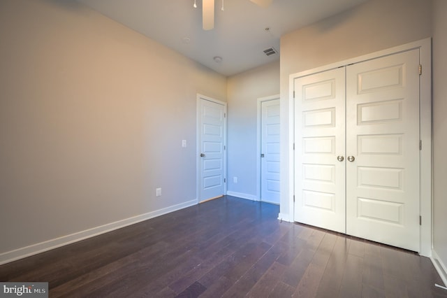 unfurnished bedroom with ceiling fan, dark wood-type flooring, and a closet