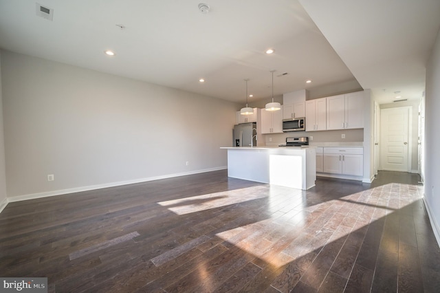 kitchen featuring a kitchen island, hanging light fixtures, appliances with stainless steel finishes, dark wood-type flooring, and white cabinets