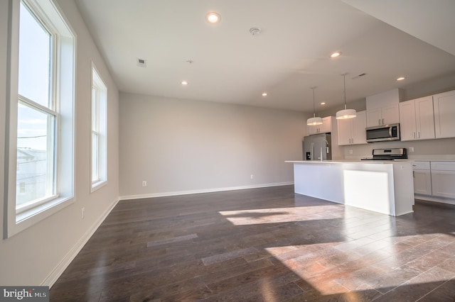 kitchen with a wealth of natural light, white cabinetry, a center island with sink, and stainless steel appliances