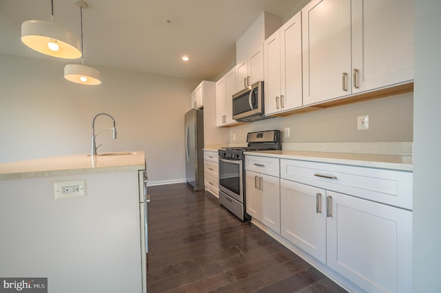 kitchen with hanging light fixtures, appliances with stainless steel finishes, sink, and white cabinetry