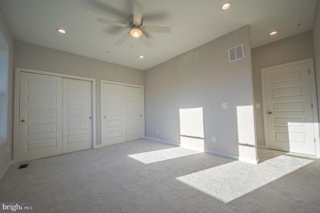 carpeted bedroom with ceiling fan and multiple closets