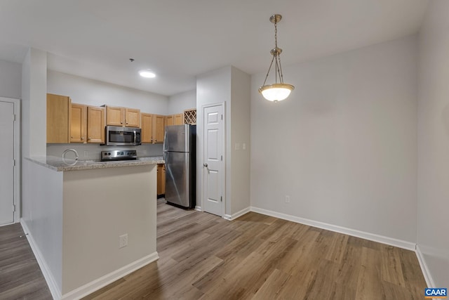 kitchen with kitchen peninsula, stainless steel appliances, light wood-type flooring, light brown cabinetry, and pendant lighting