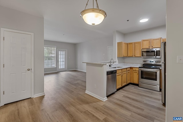 kitchen with light brown cabinets, stainless steel appliances, sink, kitchen peninsula, and light hardwood / wood-style flooring