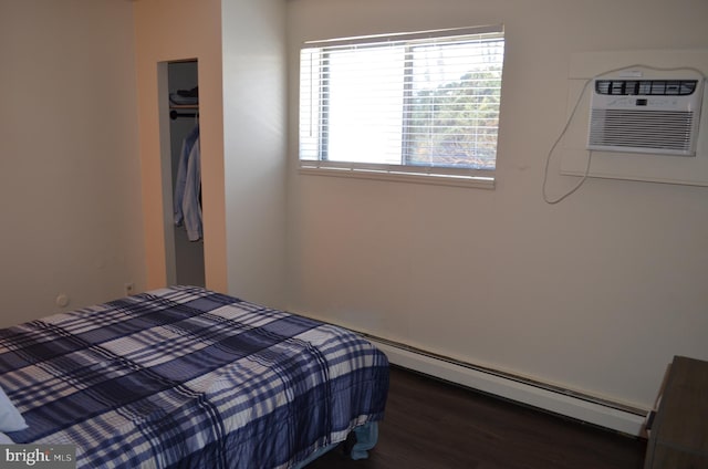 bedroom featuring a closet, dark hardwood / wood-style floors, an AC wall unit, and baseboard heating