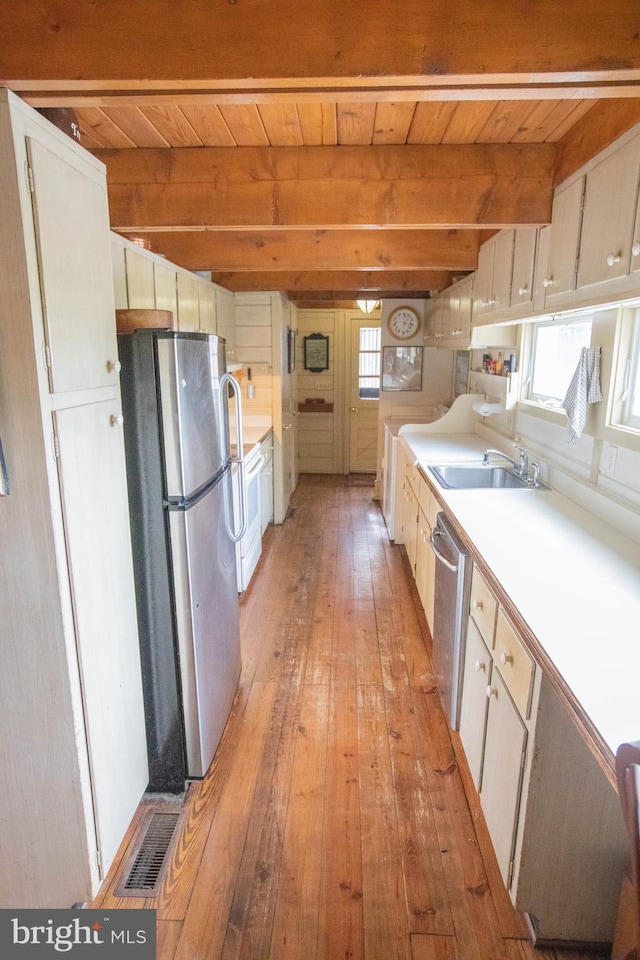 kitchen featuring white cabinetry, sink, beam ceiling, and stainless steel appliances