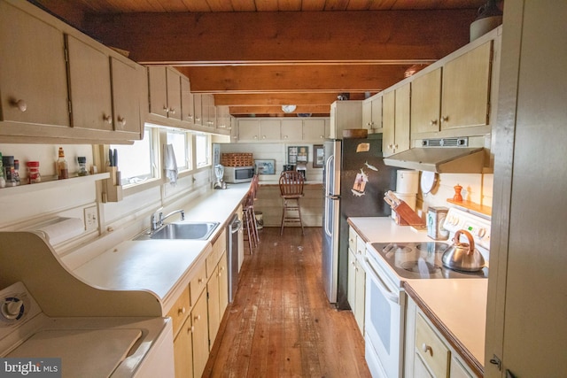 kitchen with beamed ceiling, appliances with stainless steel finishes, sink, and light hardwood / wood-style floors