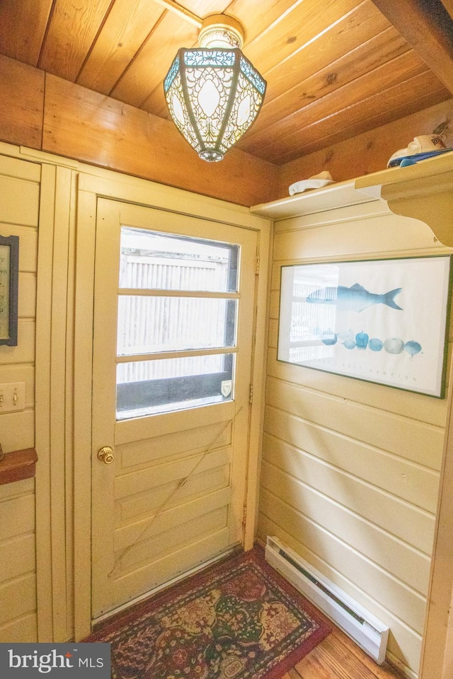 entryway with plenty of natural light, wooden ceiling, wood walls, and a baseboard heating unit