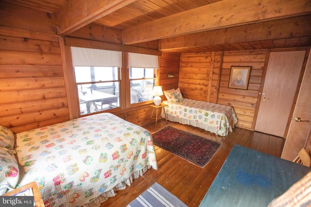 bedroom featuring wood-type flooring, wooden walls, and beamed ceiling