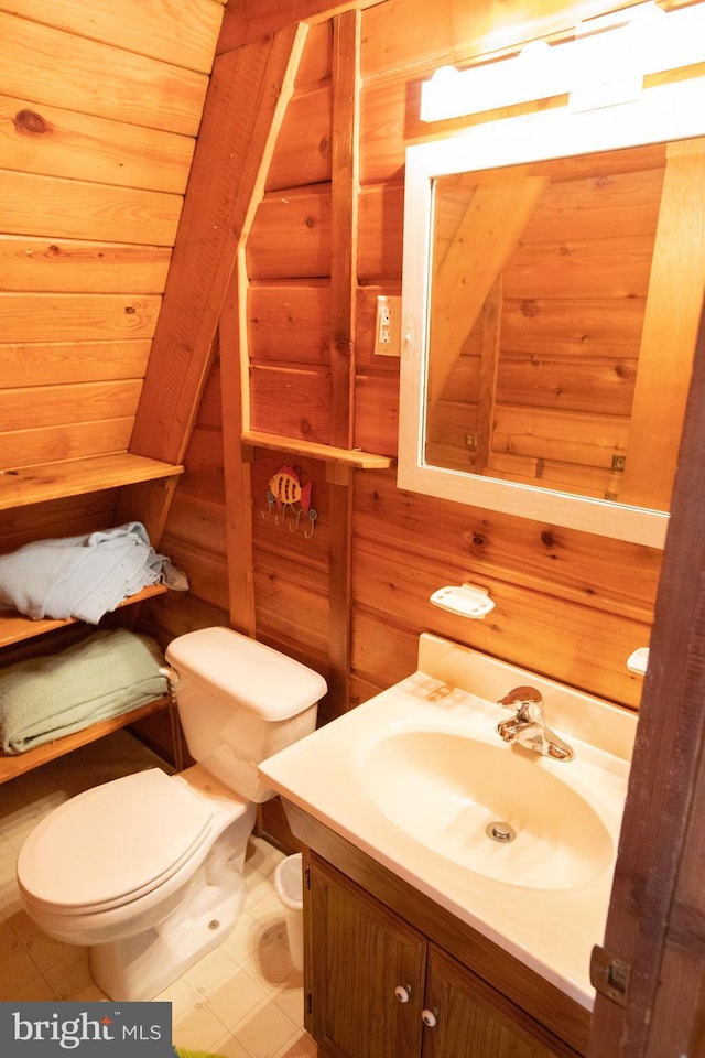 bathroom featuring toilet, vanity, and wooden walls