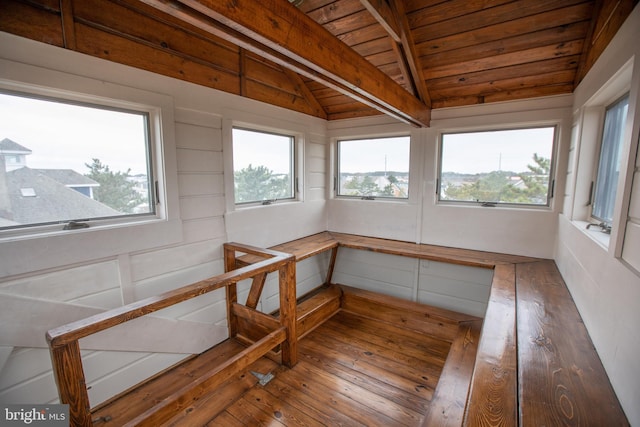 unfurnished sunroom with vaulted ceiling with beams, a wealth of natural light, and wooden ceiling