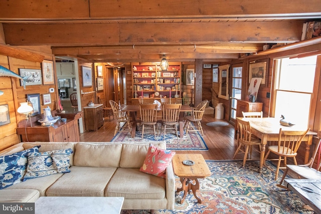 living room with beam ceiling, hardwood / wood-style floors, and wood walls