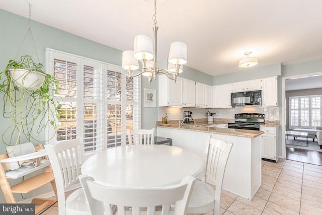 kitchen featuring black microwave, a chandelier, white cabinetry, electric stove, and backsplash