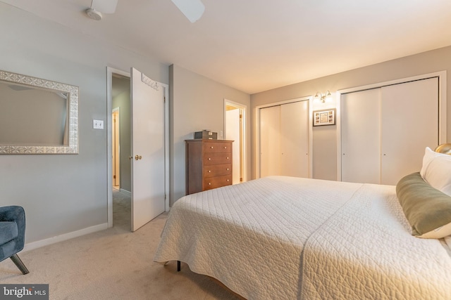 bedroom featuring light carpet, baseboards, and multiple closets