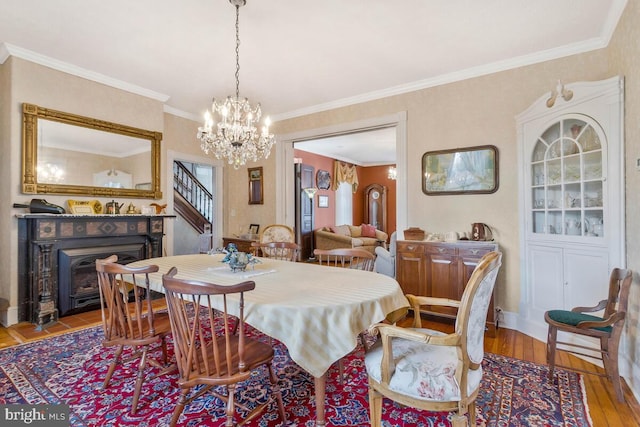 dining area with crown molding, baseboards, stairway, wood-type flooring, and an inviting chandelier